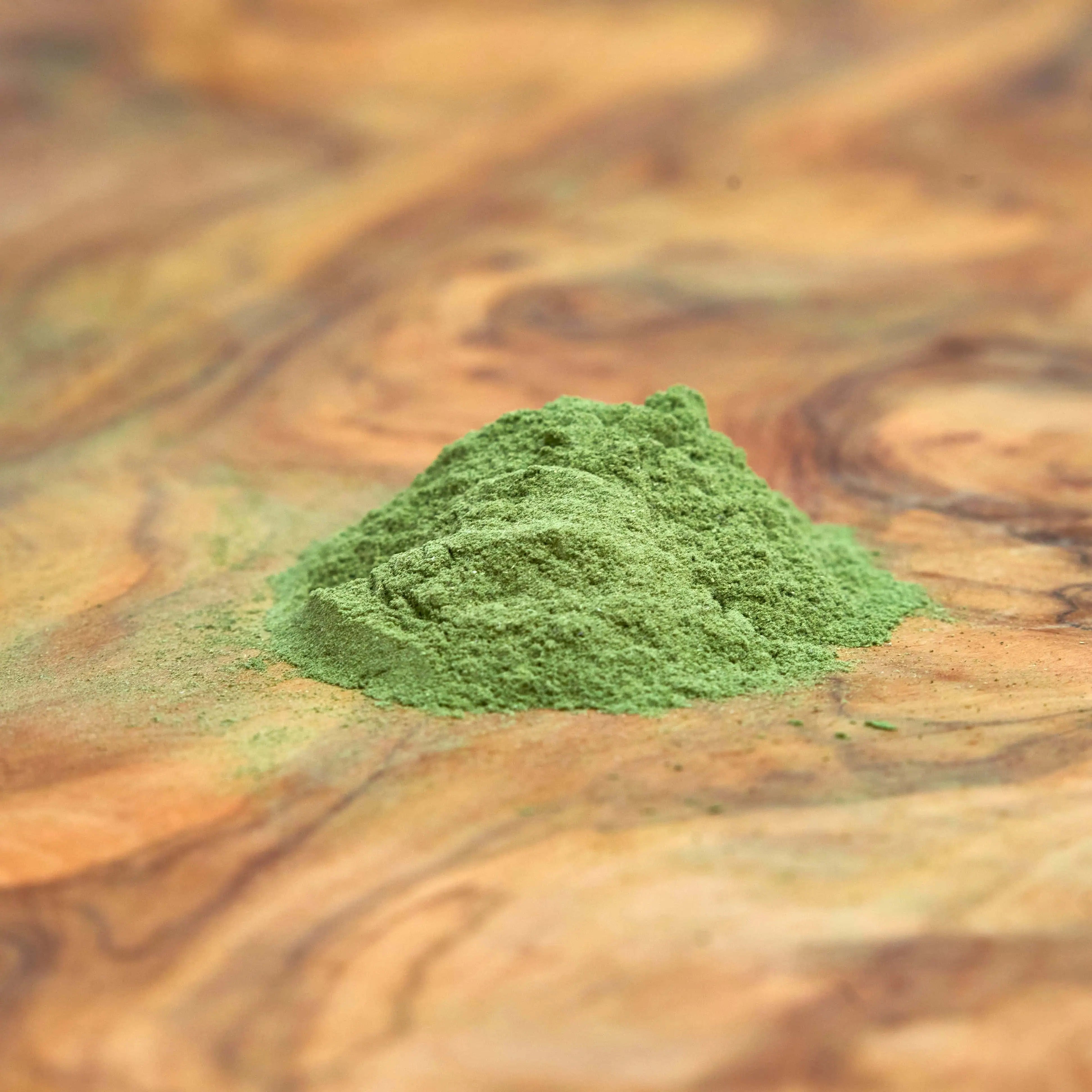 Kräftig grünes Artemisia annua Kräuterpulver aus natürlichen Heilpflanzen auf einem edlen Holzbrett, 100% Demeter-Qualität, ideal zur Förderung von Wohlbefinden und Gesundheit