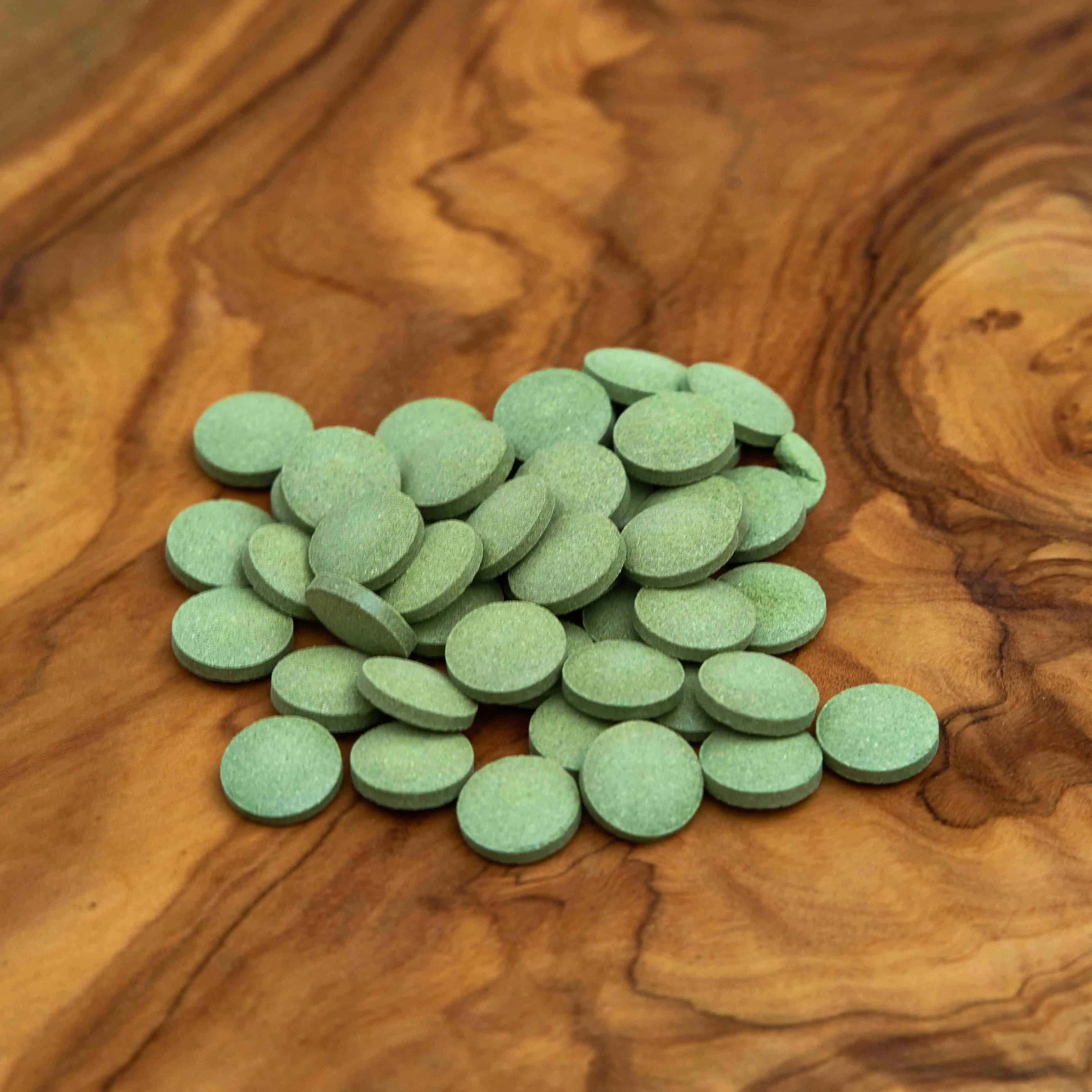Lose Artemisia annua Kräutertabs aus natürlichen Heilpflanzen auf einem edlem Holzbrett, 100% Demeter-Qualität, ideal zur Förderung von Wohlbefinden und Gesundheit