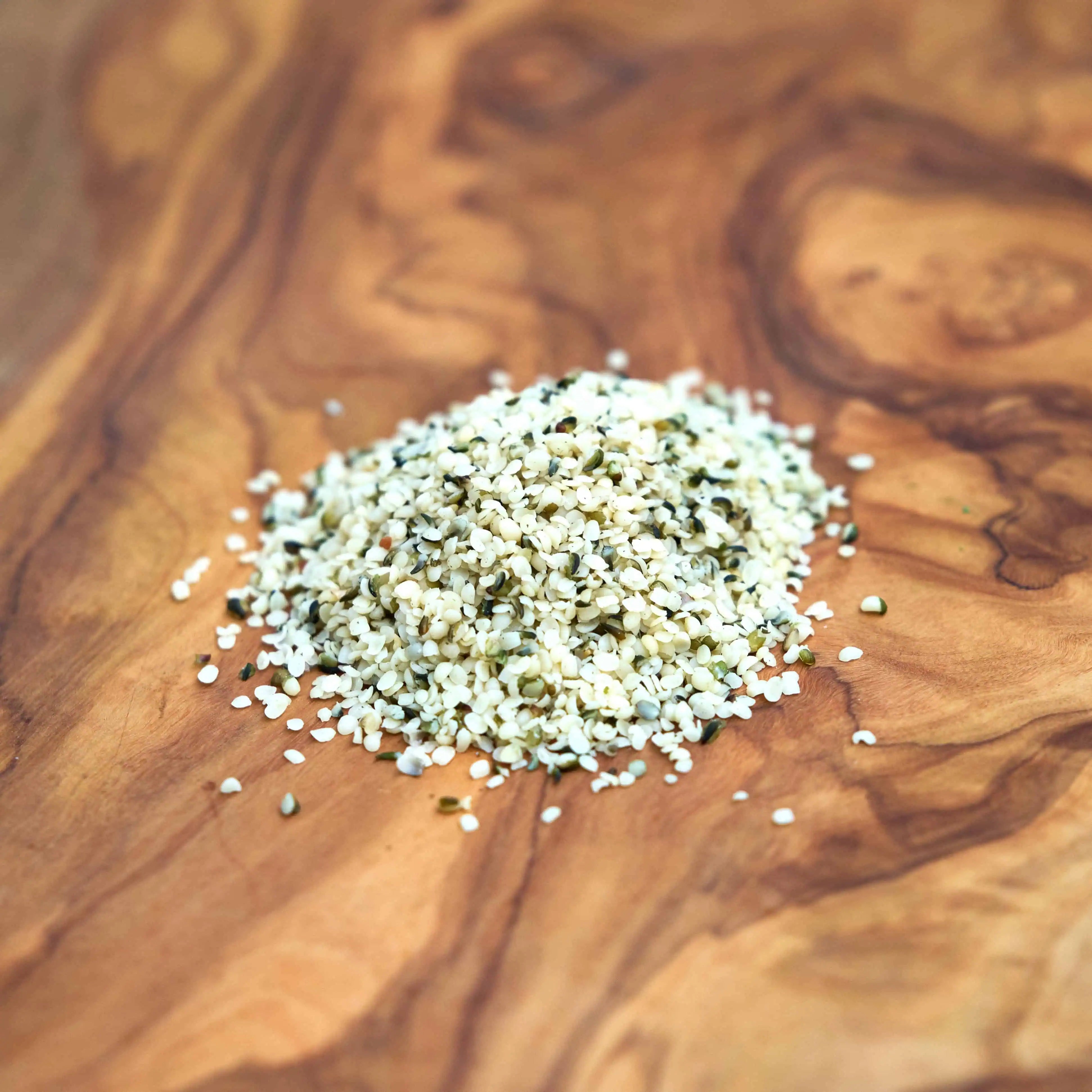 Lose Hanfsamen geschält aus nachhaltigem Hanfanbau auf einem edlen Holzbrett, 100% Demeter-Qualität, ideal zur Förderung von Wohlbefinden und Gesundheit